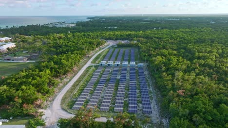 aerial orbiting shot of alternative solar panel units between exotic landscape of dominican republic - producing cheap energy for hotel and resort in punta cana - caribbean sea in background