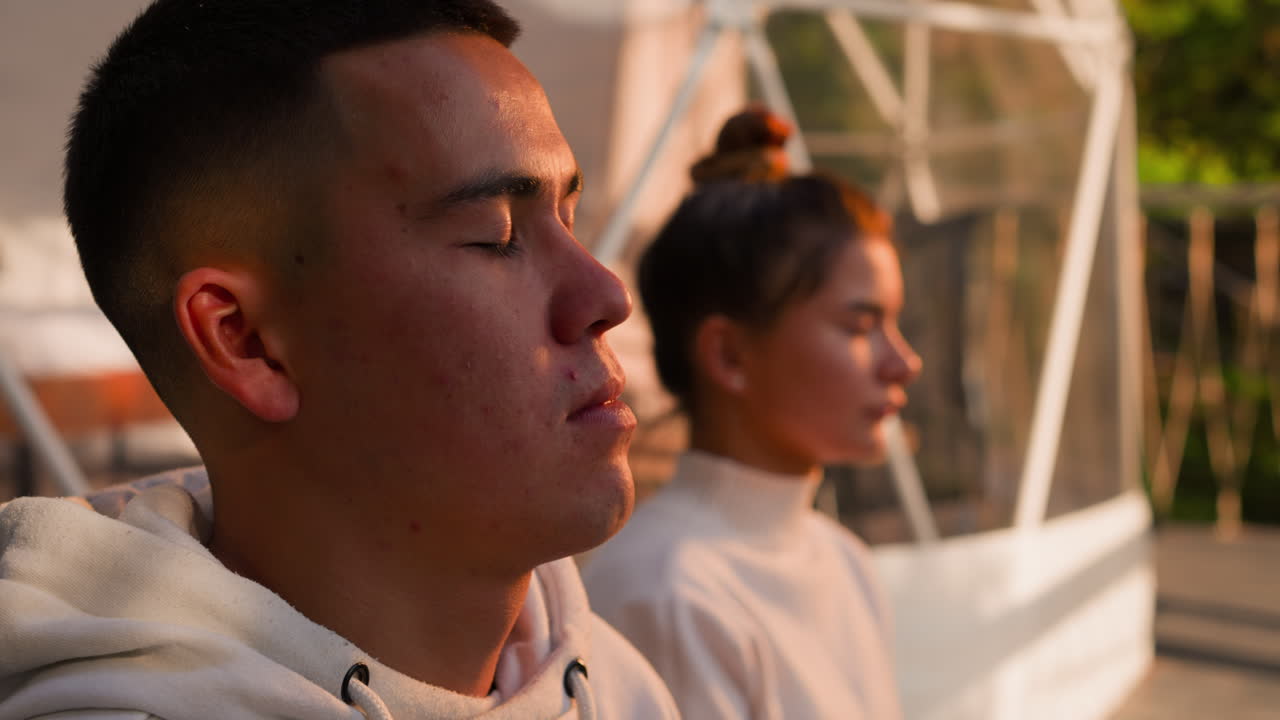 자매와 형제는 명상 중에 눈을 감고, 남녀가 동기화된 호흡을 하며, 공유된 연습의 평온 속에서 더 깊이 잠수한다.
