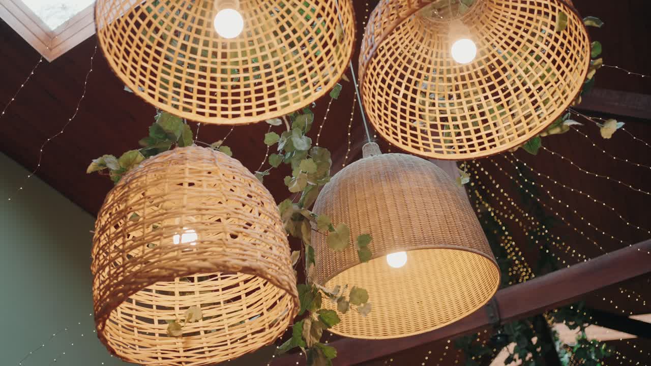 Natural wicker lamps glowing warmly with hanging greenery accents
