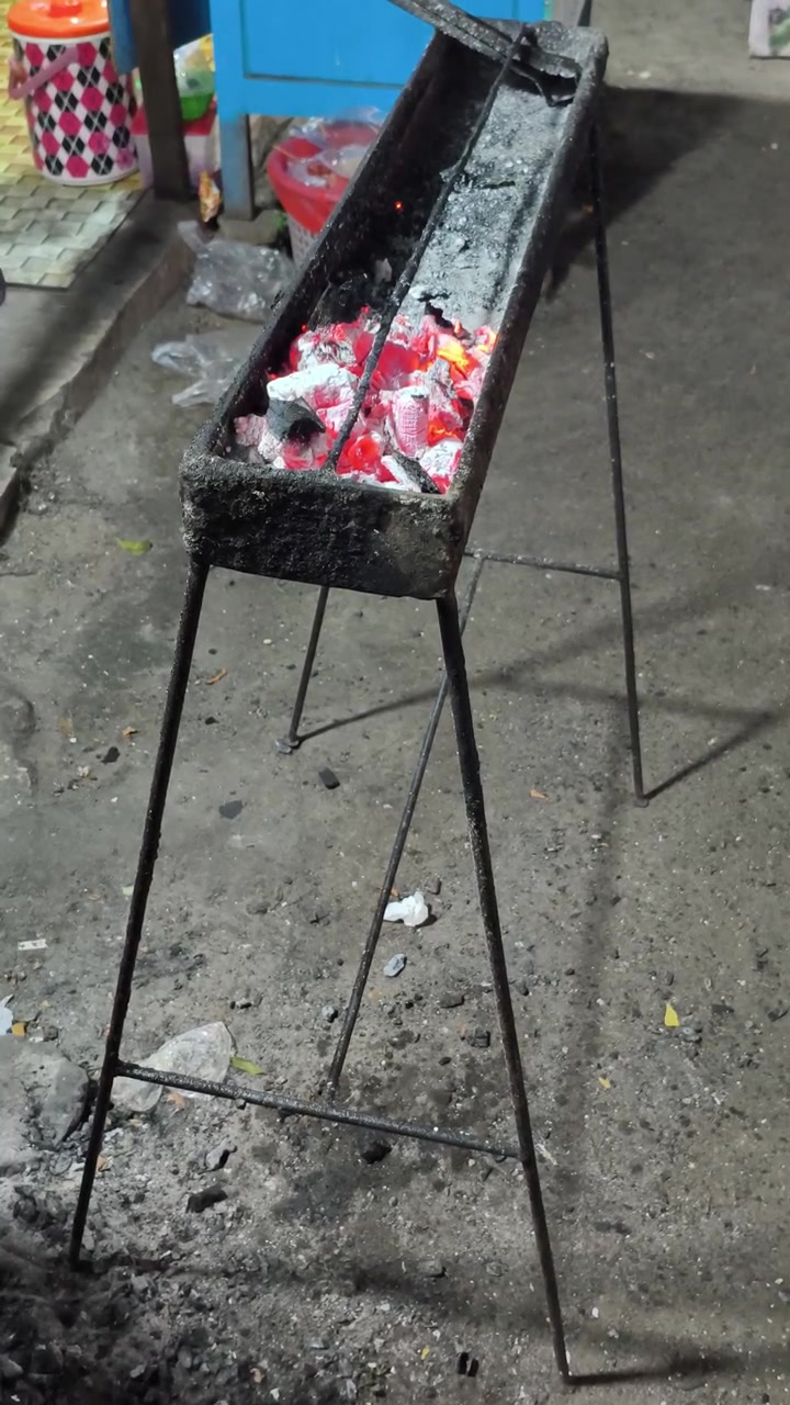 Carbonella ardente in una griglia di metallo per cucinare all'aperto.