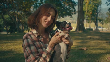 woman holding boston terrier in a park