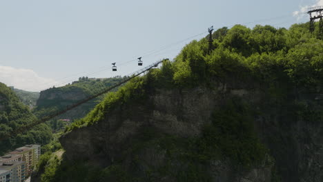 rusty material ropeway with cargo containers above rock cliff, georgia