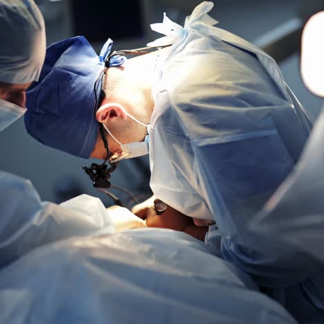 doctors during surgery. operating process by professional surgeons under medical lamp. medical specialist and male assistant doing a surgery.