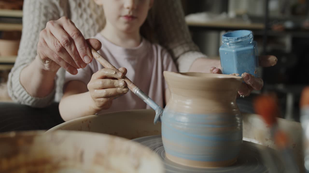 la abuela enseña a su nieta a trabajar en una rueda giratoria de cerámica