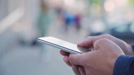 4k young man uses smartphone on street in city. close-up of smartphone in hands