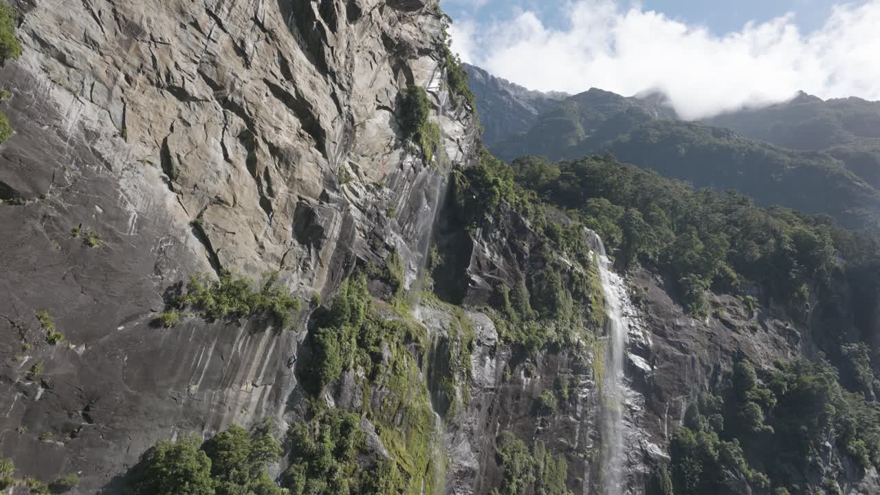 vista de cascadas en las montañas durante un soleado día de verano en milford sound, fiordland, nueva zelanda