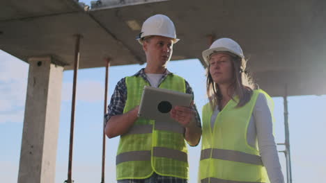 supervisor de un edificio en construcción hombre discutiendo con ingeniero diseñador mujer el progreso de la construcción y examina un plan de construcción.