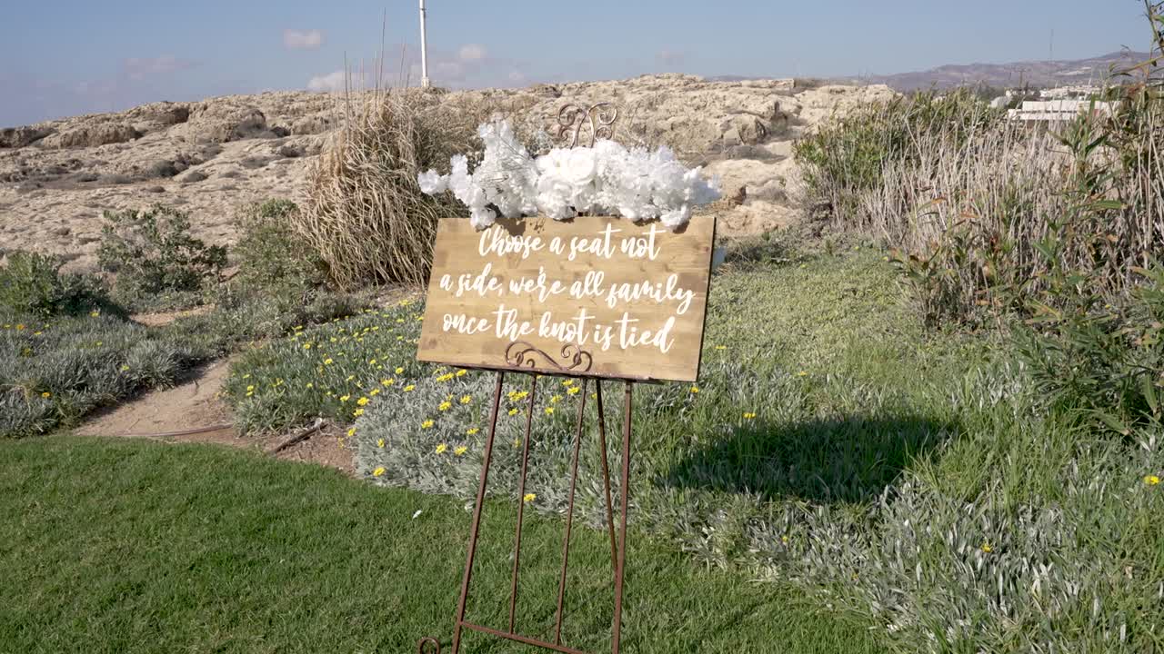 L'ambientazione mostra una famiglia riunita in uno spazio all'aperto con elementi naturali. Un cartello sottolinea l'idea di unità in famiglia. La scena presenta vegetazione e nuvole leggere nel cielo.