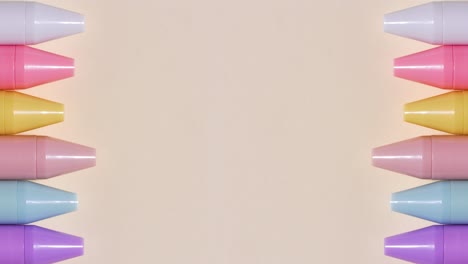 pastel pens shuffle in stop motion on a beige surface, wide central copy space, loopable