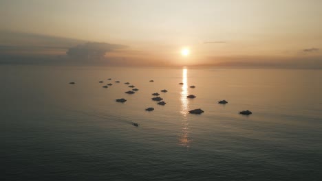 salida del sol tomada desde el aire, barcos flotando en el océano, reflejo del sol en el mar tranquilo, atmósfera cinematográfica