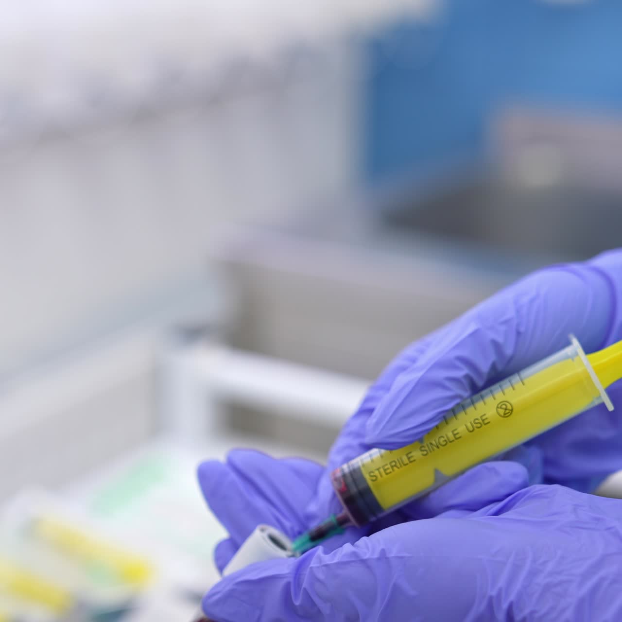 Female nurse's hands in protective latex glove fill the test tube with blood from a syringe. Close up. Blood test analysis in laboratory