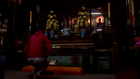 the woman kneels at the altar in a buddhist temple and prays.