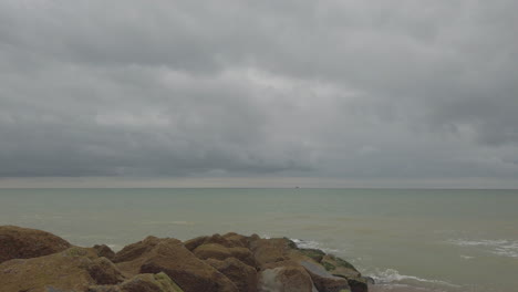 Brighton-Beach-An-Einem-Bewölkten-Tag-Mit-Möwen,-Die-An-Der-Kamera-Vorbeifliegen,-Schuss-Am-Strand-Entlang-Schwenken