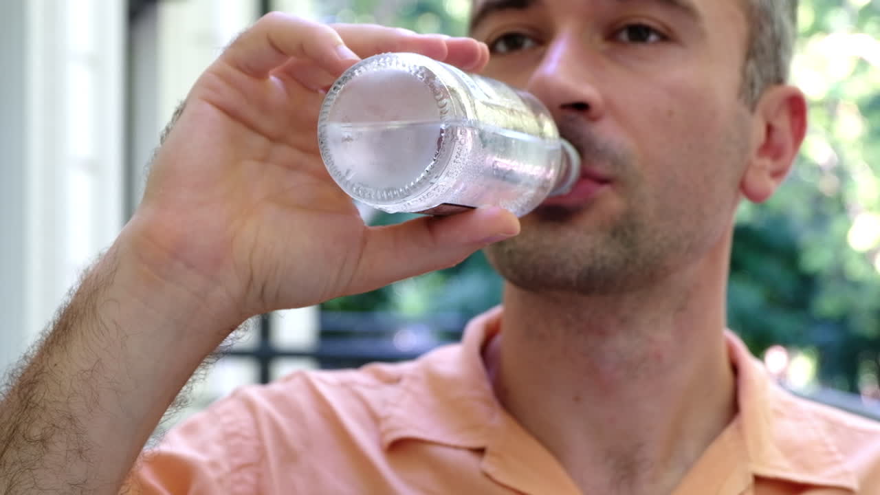 Close up of a man drinking a bottle of water at a terrace