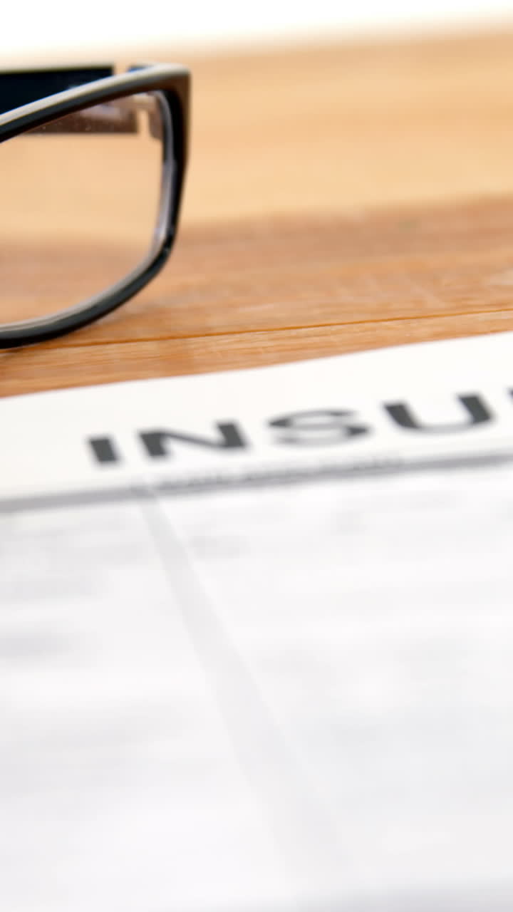 Close-up of insurance contract, pen and spectacle