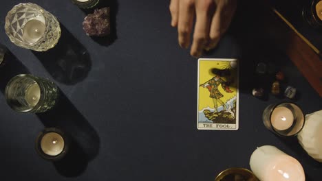 overhead shot of person giving tarot card reading laying down the fool card on table 1