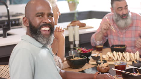 enjoying meal with friends, senior man smiling and dining at home