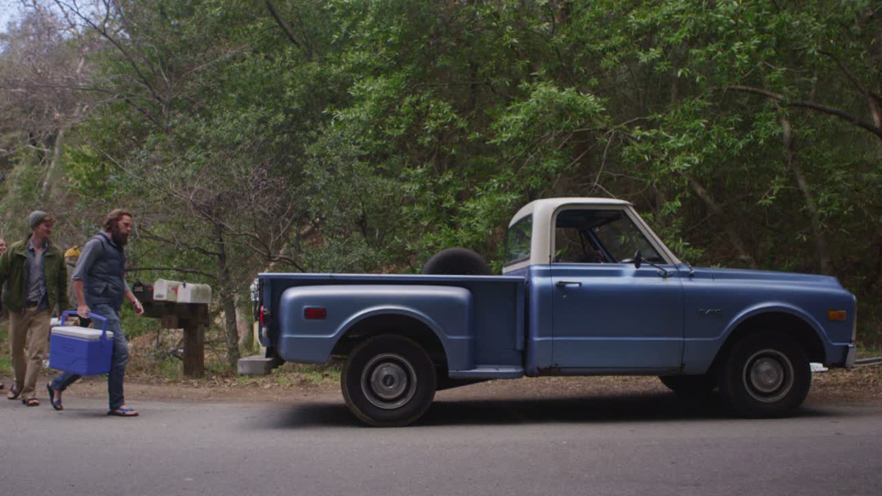 한 그룹이 캠핑 여행을 준비하기 위해 파란색 픽업 트럭에 장비를 싣고 있습니다.