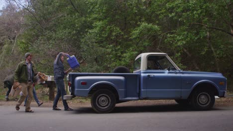 un grupo carga equipo en una camioneta azul en preparación para un viaje de campamento