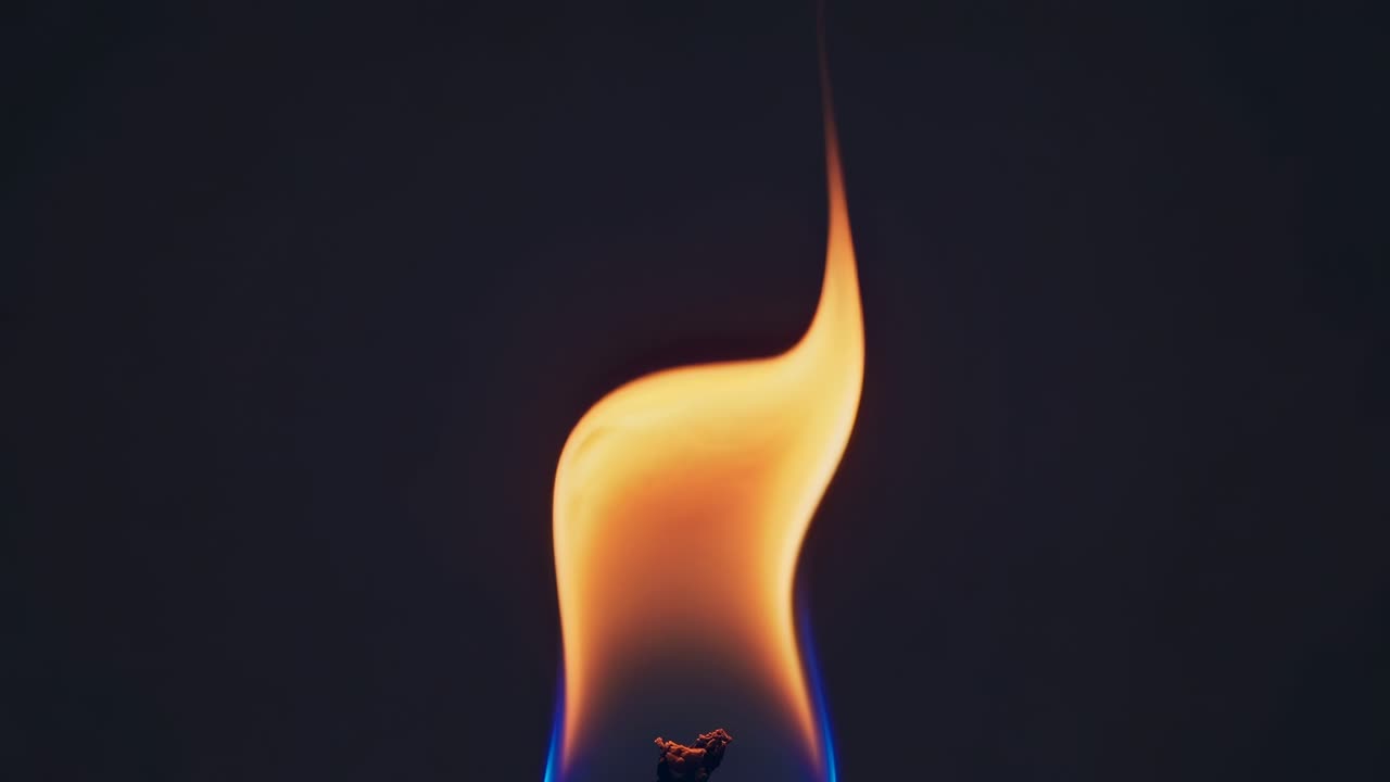 Close-up, low-angle shot of a candle flame against a dark background, creating a dramatic