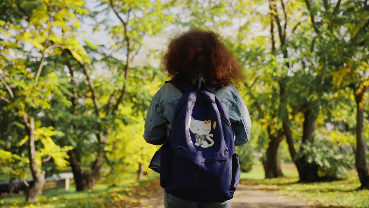 Young Woman with Backpack Walking in Autumn Park