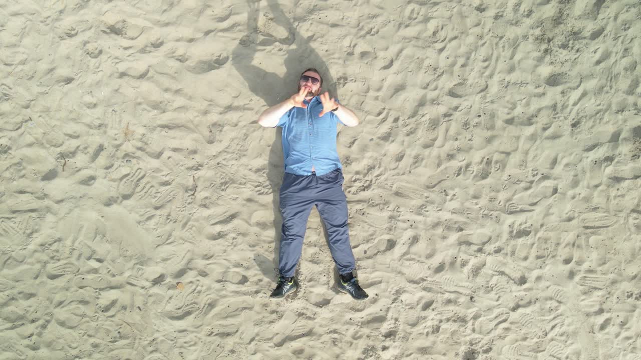 Caucasian Man Rapping While Lying On Sand At Donabate Beach In Ireland. overhead shot