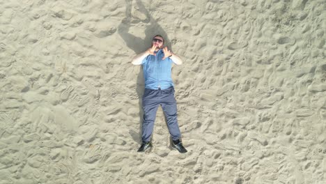 caucasian man rapping while lying on sand at donabate beach in ireland. overhead shot