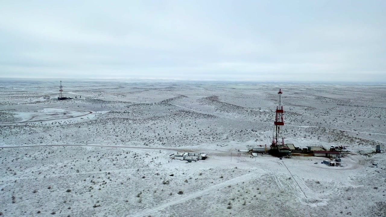 Bredt luftfoto af frosset olie- og gasfelt med boreinfrastruktur