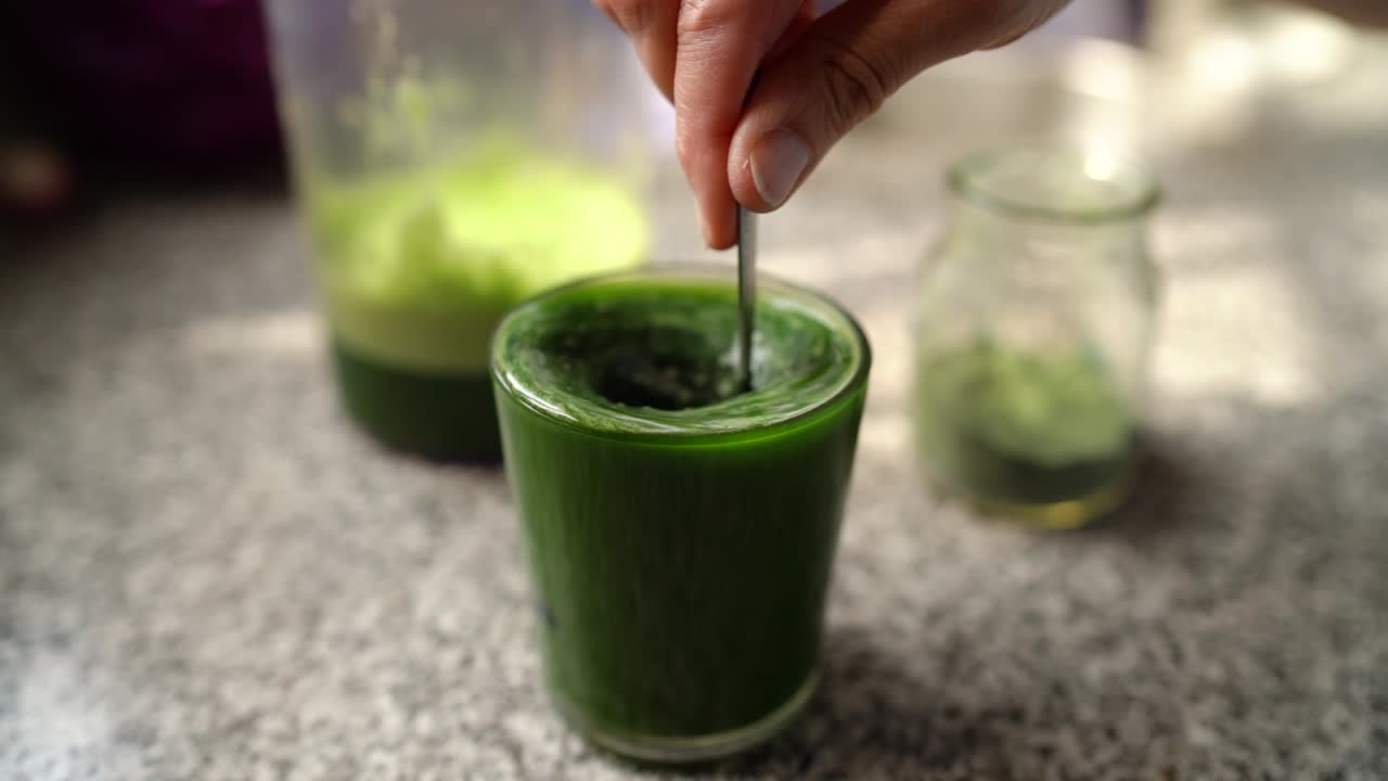 Aggiungere spirulina a un bicchiere di salutare verdura verde