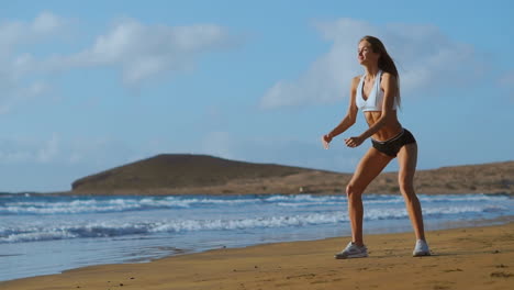 sportswoman wearing sportswear doing squats exercise outdoors. fitness female working out on the beach at sunset. athletic young woman is engaged in outdoor sports.