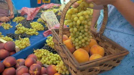 mujer poniendo uvas en una canasta en el mercado callejero