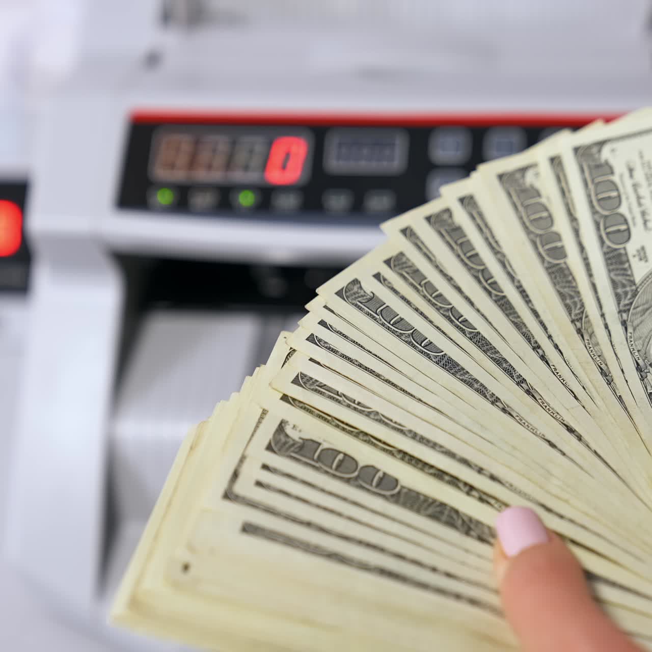 Woman holding money near counting machine at table indoors, closeup
