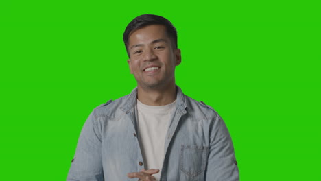 portrait of casually dressed smiling young man against green screen