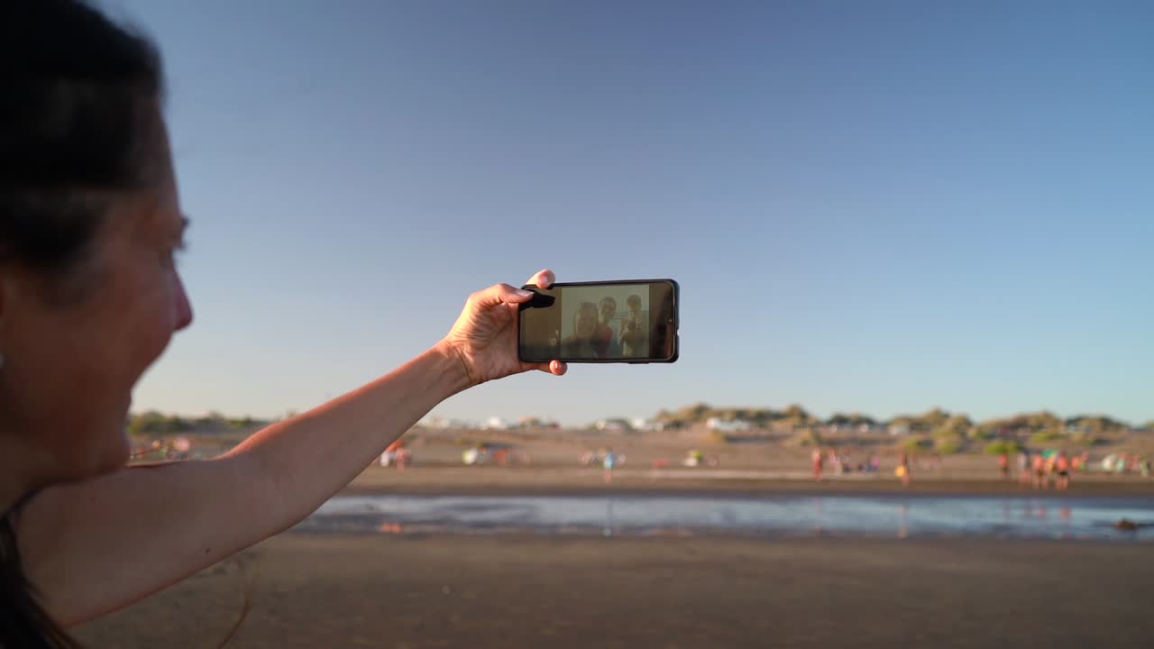 Close Up Of A Beautiful Lady Taking Selfie Using Mobile Phone Camera On A Sunny Summer Day At The Beach.
