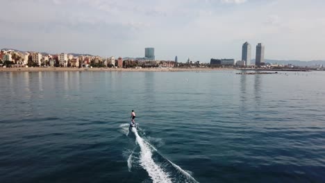 electronic surfing at the beach - electric board surfer riding along barcelona coast in spain - drone shot