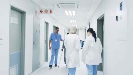 Doctors-in-hospital-corridor-pass-heathcare-worker-helping-elderly-patient-4k