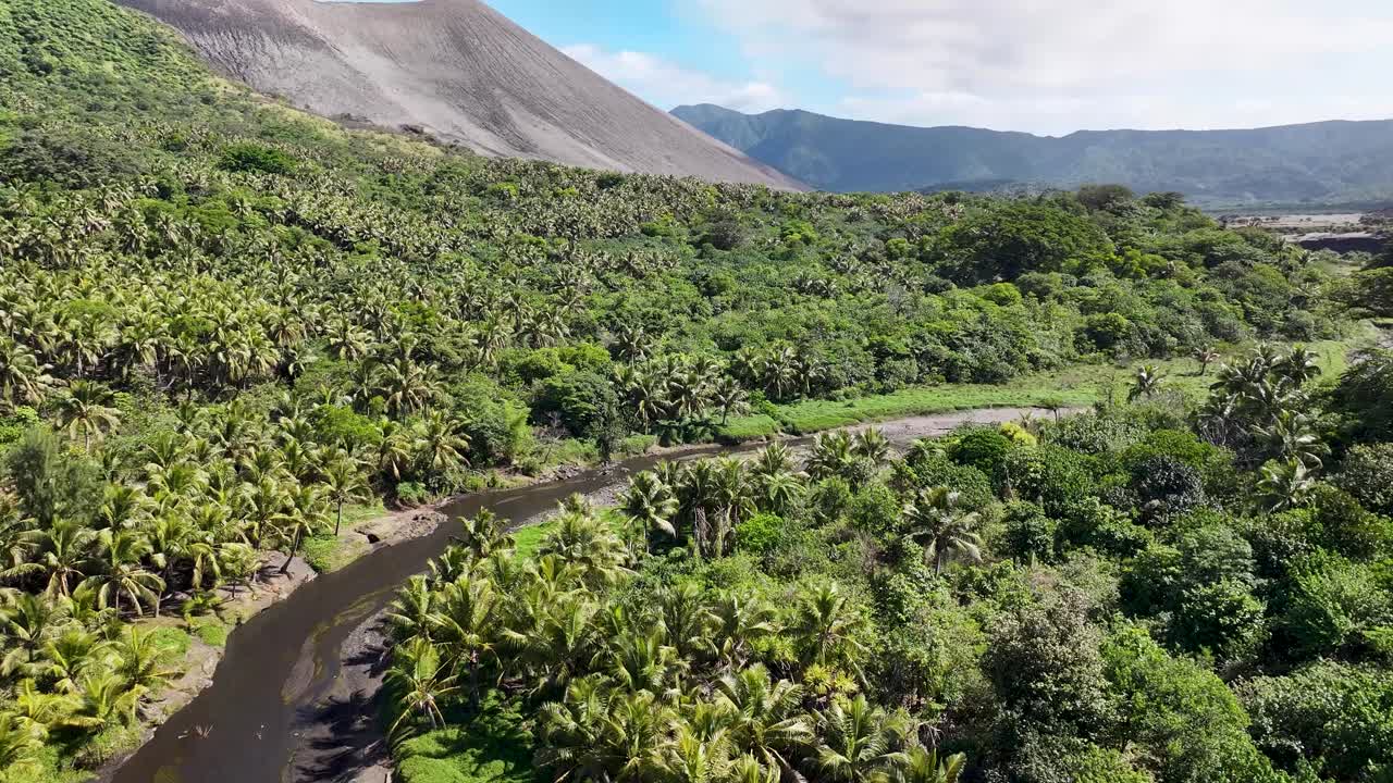 River in tropical forest and Yasur Volcano in Tanna Island, rugged landscape, Pacific Islands.