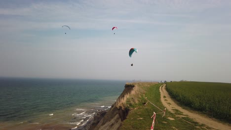 some paragliders fly along the steep coast of the baltic sea