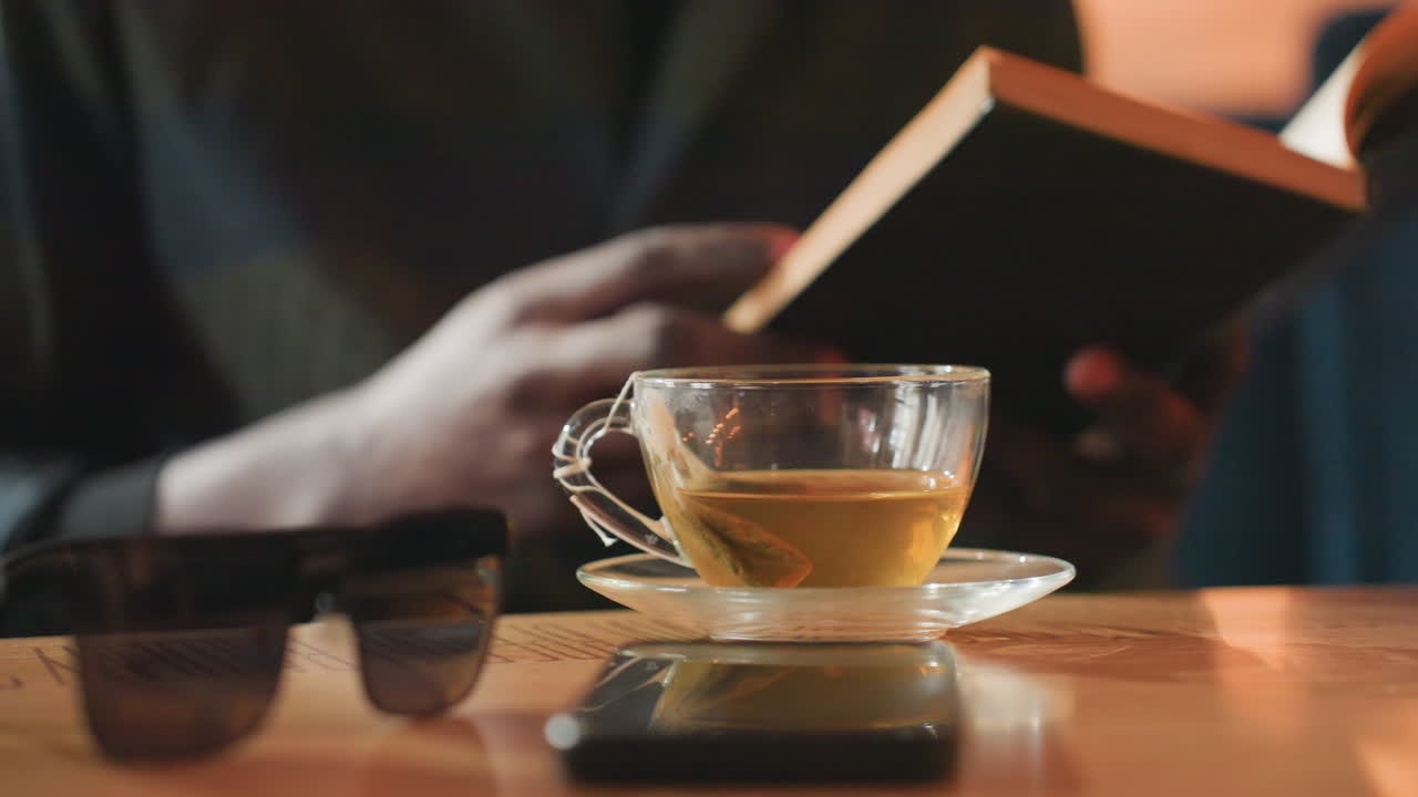 차분하게 독서하며 휴식을 취하고, 평화롭게 차와 책을 즐기는 시간, 따뜻한 음료와 흥미로운 문학 작품이 함께하는 편안한 순간, 차 한 잔과 매혹적인 독서를 즐기는 차분하고 평온한 휴식