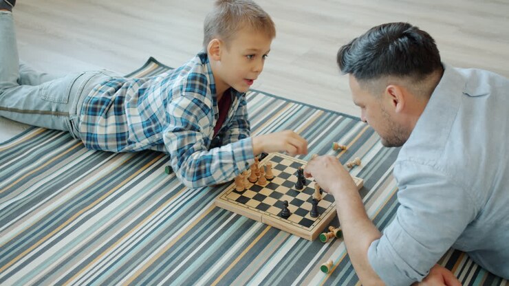 Father and son playing chess on the floor