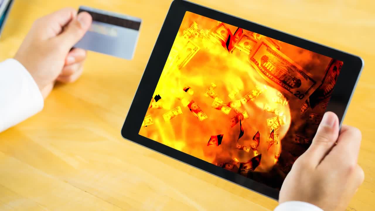 Animazione digitale di banconote di dollari che cadono sulle fiamme in un tablet digitale
