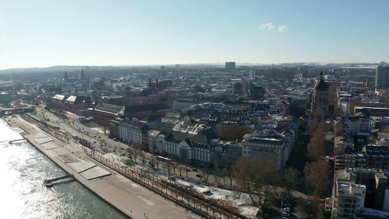 Drone flight over a snowy Mainz the City of Biontech on a sunny Winter day showing flood of the Rhine river and blue sky