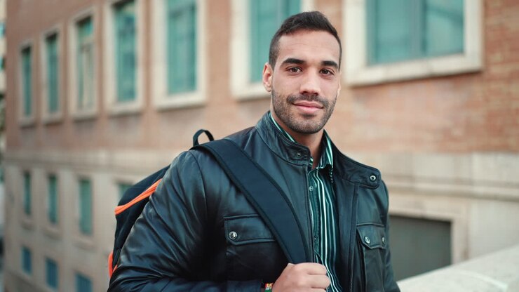 Young man with backpack standing outdoors.