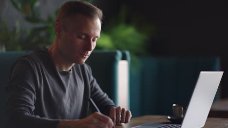 a serious man is a business student working studying sitting at a table and typing a message on a laptop. typing text on the keyboard