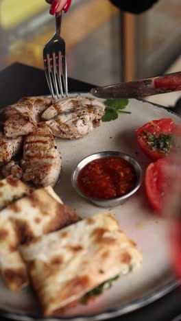 mujer comiendo pollo a la parrilla y pan pita con vino rojo