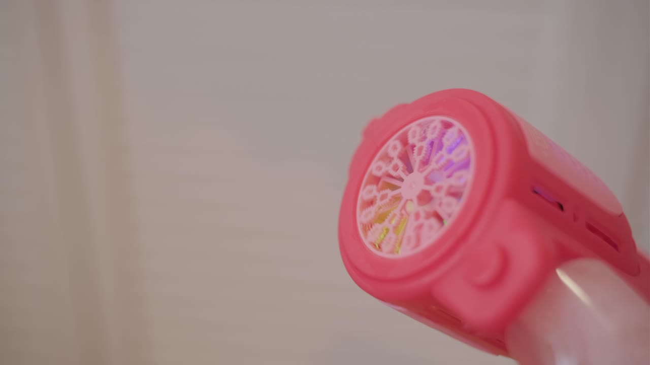 Pistola giocattolo sparabolle rosa che crea bolle.