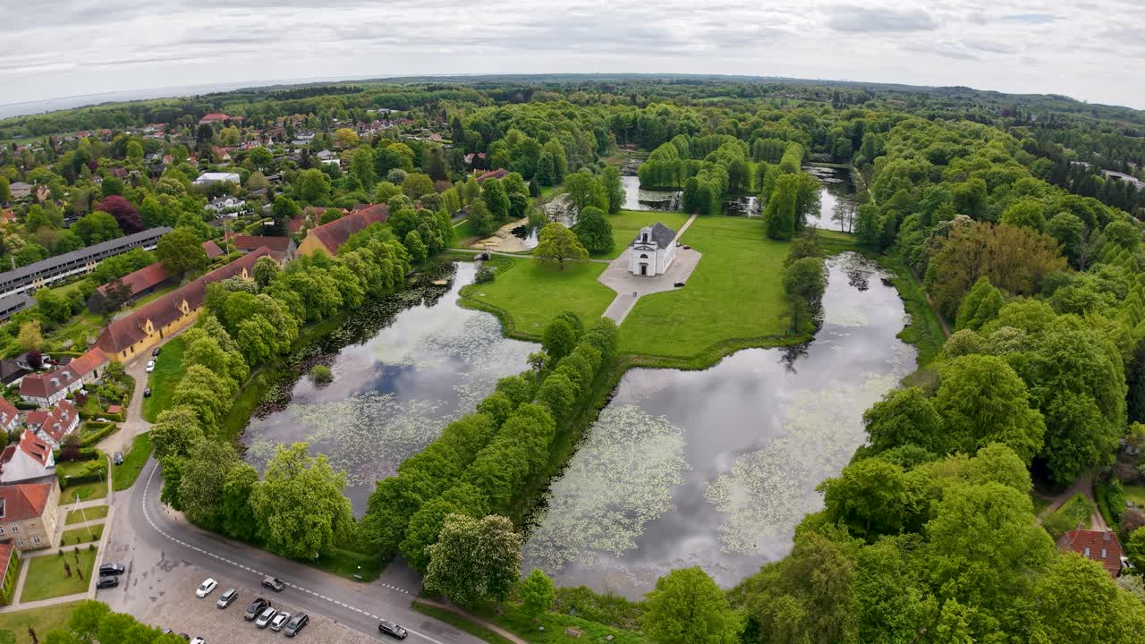 Aerial drone view of a landscaped park with reflective ponds, green trees, and surrounding residential neighborhood
