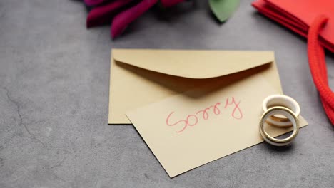 note with the sorry word next to a wedding ring