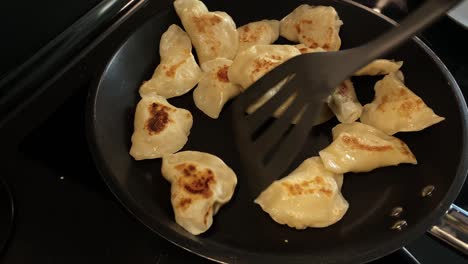 transferring fried dumplings into the pan, using a special spoon for kitchen work