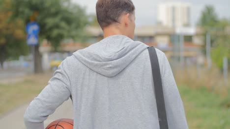 Rückansicht-Eines-Mannes,-Der-Mit-Einem-Basketball-Und-Einer-Sporttasche-Geht